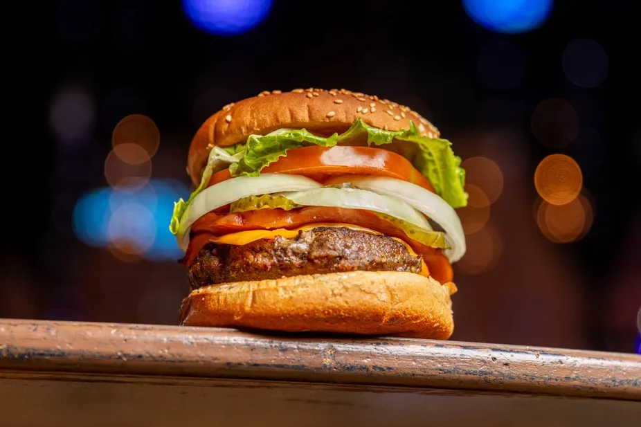 A tall homemade burger with lettuce, tomato and onion