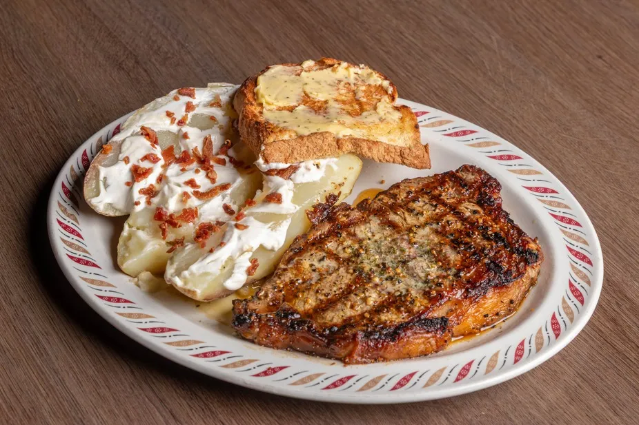 A grilled strip steak with a loaded baked potato and toast