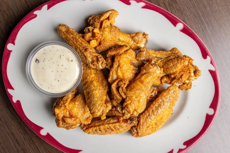 A plate of crispy wings with a cup of ranch